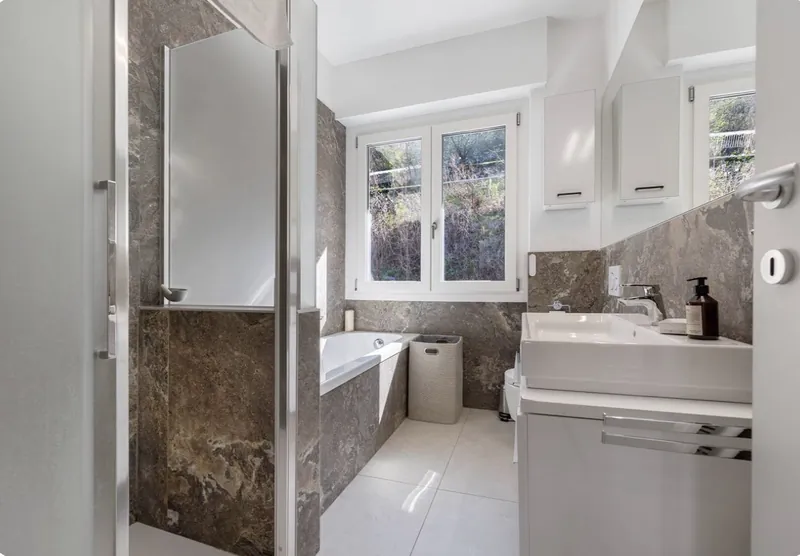 Badezimmer mit Dusche, Badewanne und Naturstein-Optik