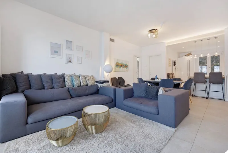 Großzügiger Wohnbereich mit zwei Sofas und goldenen Beistelltischen
