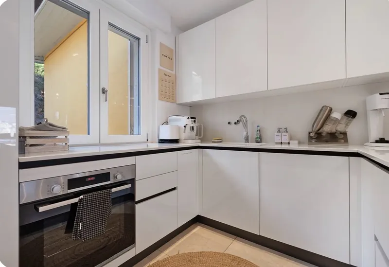 Küchenzeile mit Backofen, Kaffeemaschine und Fenster