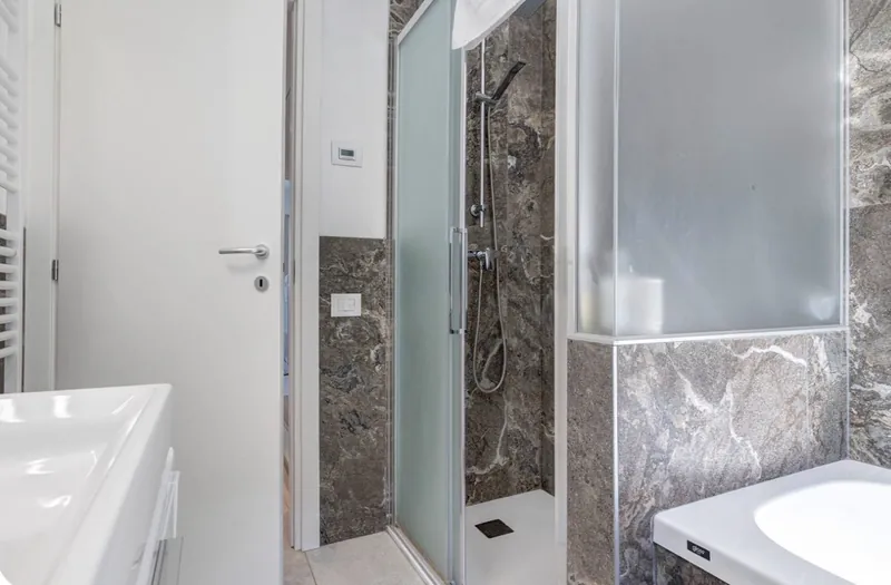 Ebenerdige Dusche mit Glastür und Steinfliesen