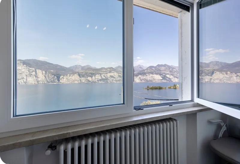 Seeblick aus dem Fenster mit Insel und Bergpanorama